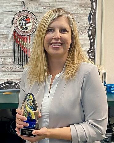 woman in beige cardigan holding merit award