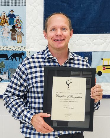 man in checkered shirt holding framed certificate