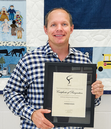 man in checkered shirt holding framed certificate
