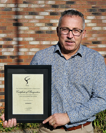 man in patterned shirt holding framed certificate