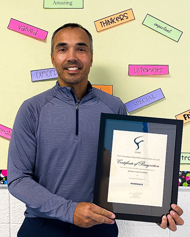 man in blue striped half zip shirt holding framed certificate