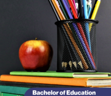 cup of pens and pencils sitting on a stack of books with an apple