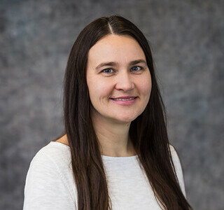 woman with long straight dark hair smiling for the camera