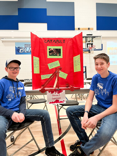 two middle school students posing in front of their science fair display