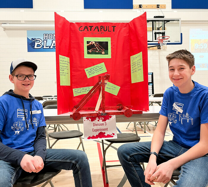 two middle school students posing in front of their science fair display