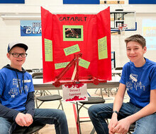 two middle school students posing in front of their science fair display