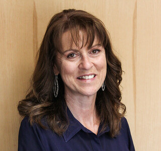 woman with long wavy brown hair smiling for the camera