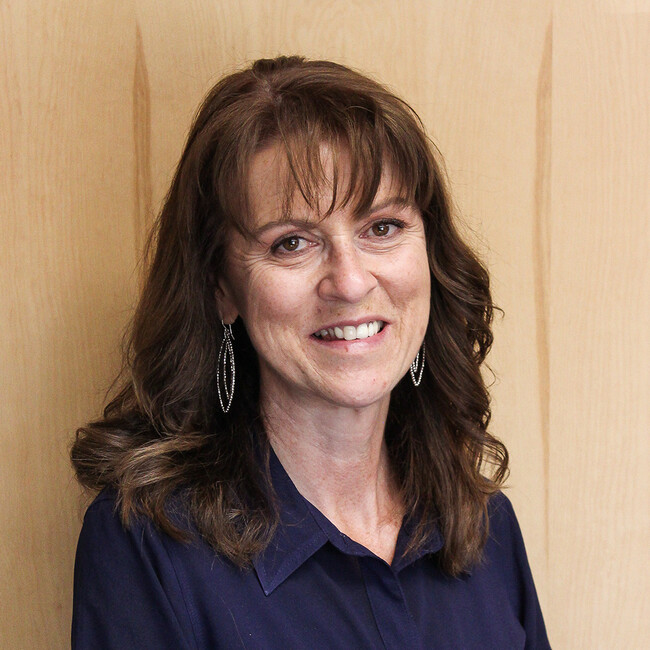 woman with long wavy brown hair smiling for the camera