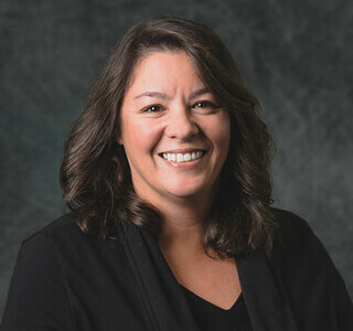 woman with wavy dark hair smiling for the camera