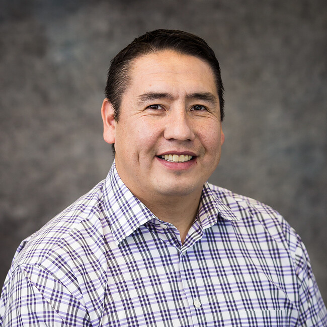 man in checkered button up shirt smiling for the camera