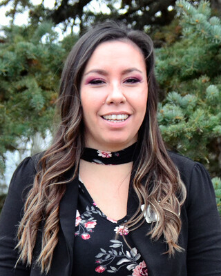 woman with long dark brown hair wearing a black blazer and flowered blouse