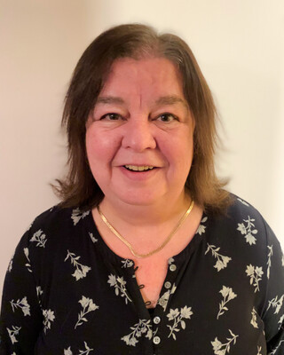 woman with chin length brown hair wearing a black flowered shirt