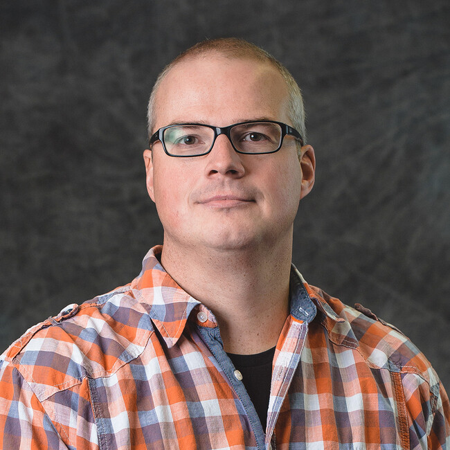 man wearing plaid shirt and glasses posing for the camera