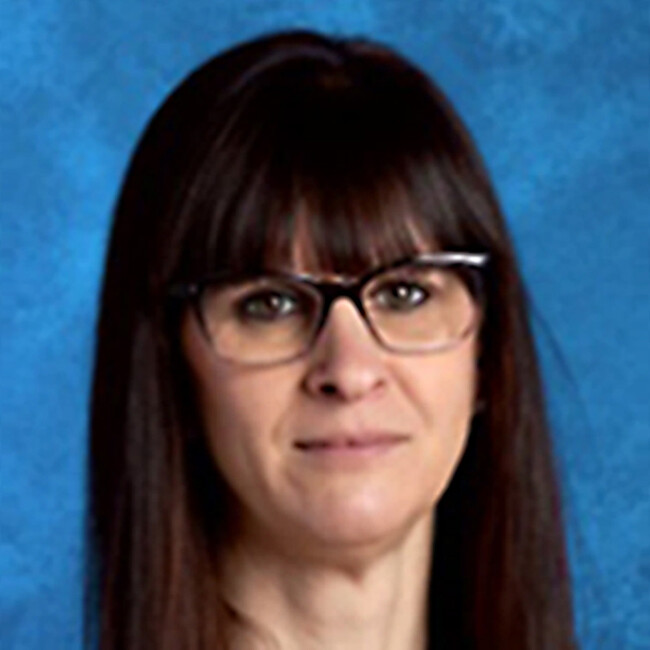 woman with long straight dark hair and glasses smiling for the camera