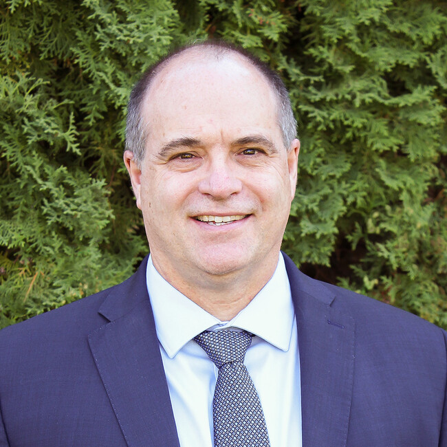 man in a blue suit and tie smiling for the camera