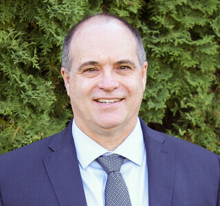 man wearing a blue suit and tie smiling for the camera