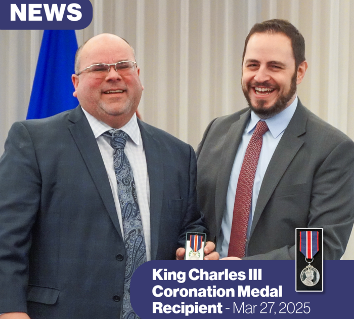 two men smiling and posing for the camera as one presents the other with a medal