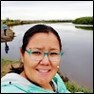 woman with dark hair and teal eyeglasses with a river in the background