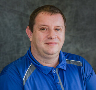 man in blue polo shirt smiling for the camera