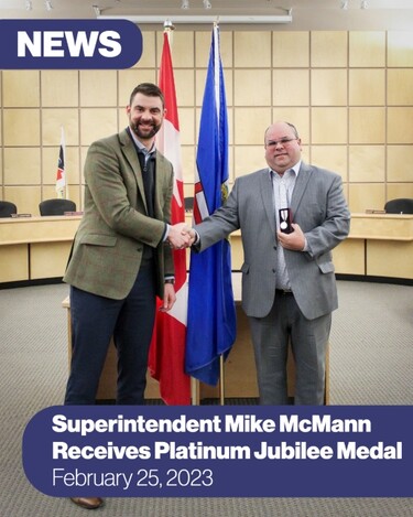 one man in a suit presenting another man in a suit with a medal