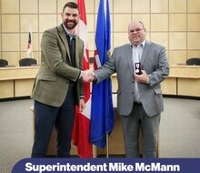one man in a suit presenting another man in a suit with a medal