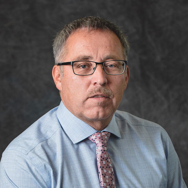 man wearing glasses and a shirt and tie smiling for the camera