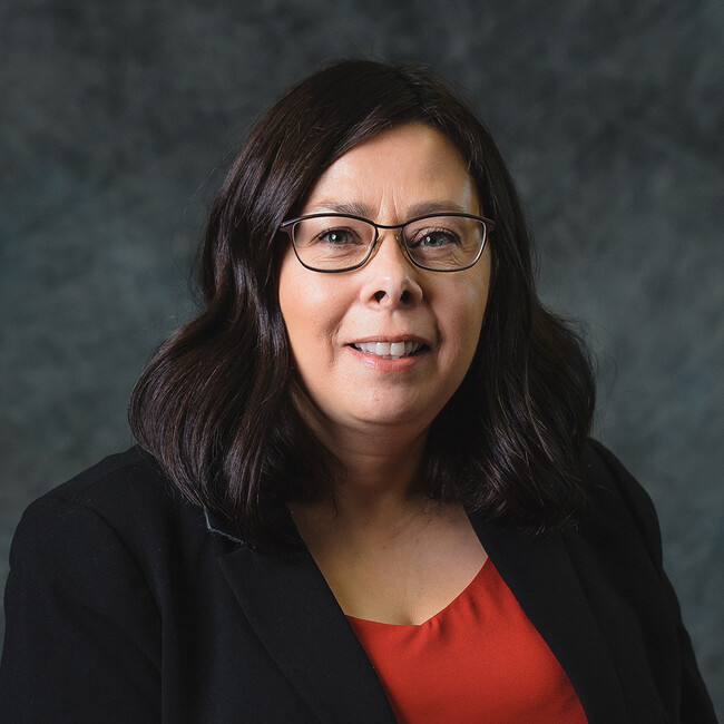 woman with wavy dark hair and glasses smiling for the camera