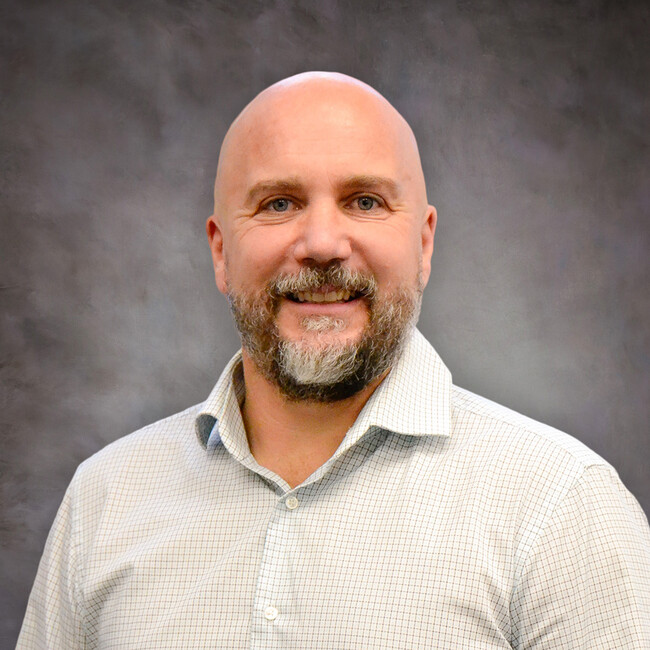 man wearing a white button up shirt smiling for the camera